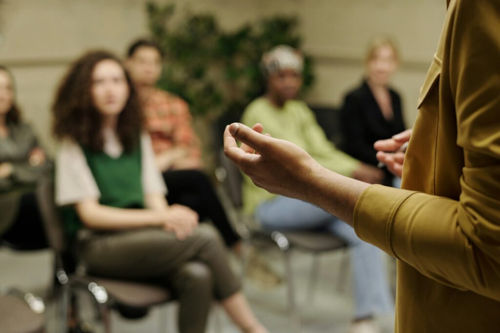 Hands of young business coach explaining information to group of employees