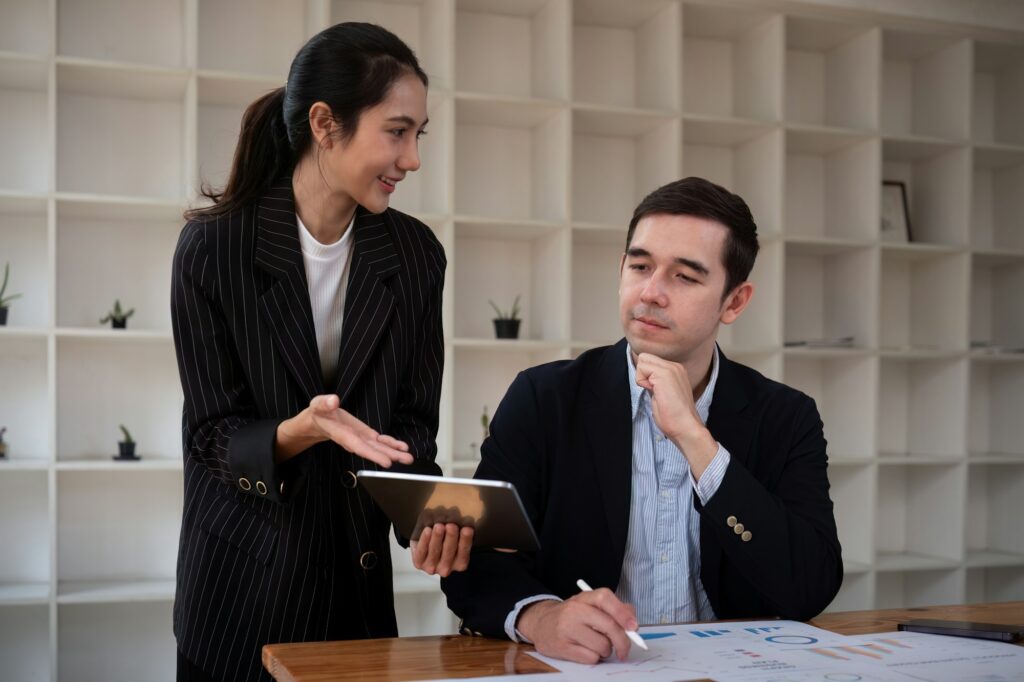 Team business of diverse partner business woman discuss project on laptop sitting at table in